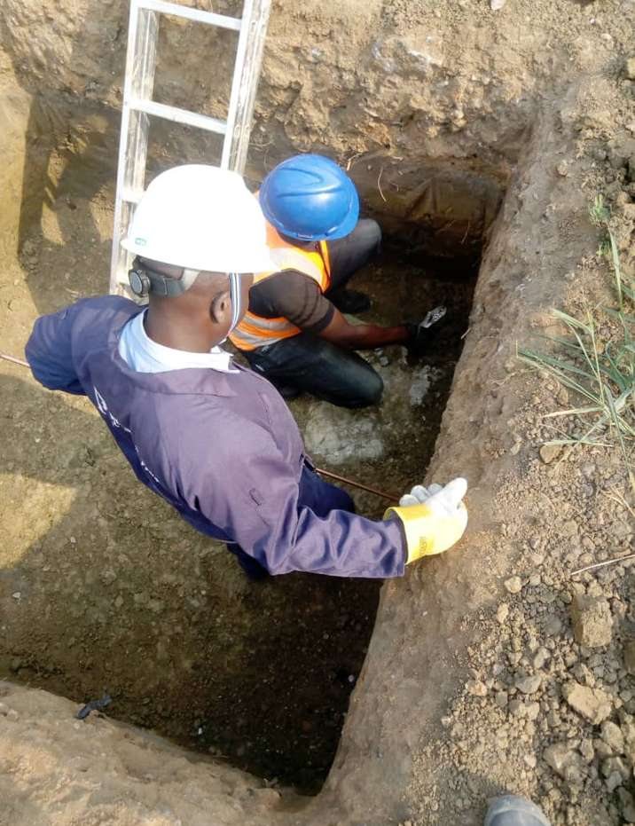 Workers installing an earth rod in an excavated pit