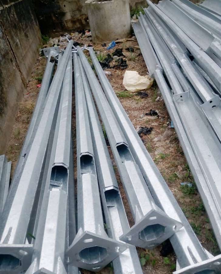 Galvanised lighting poles stacked at a laydown area