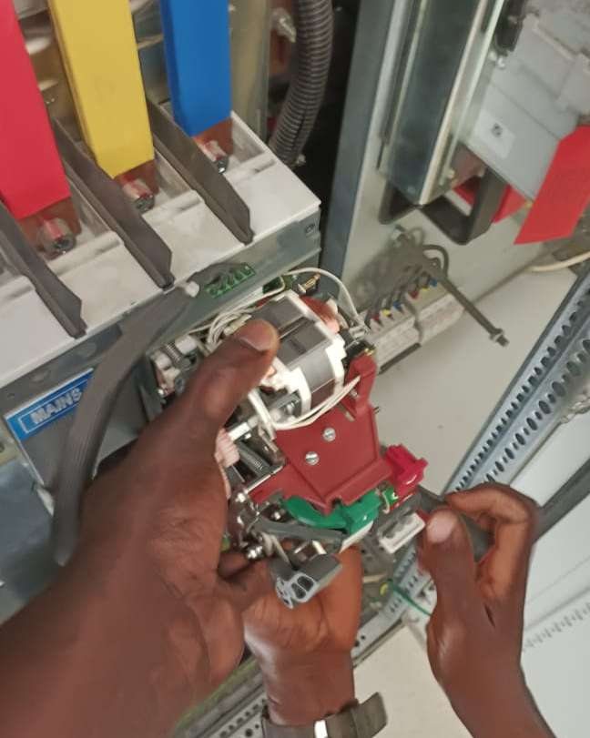 Hands servicing a motorized circuit breaker mechanism